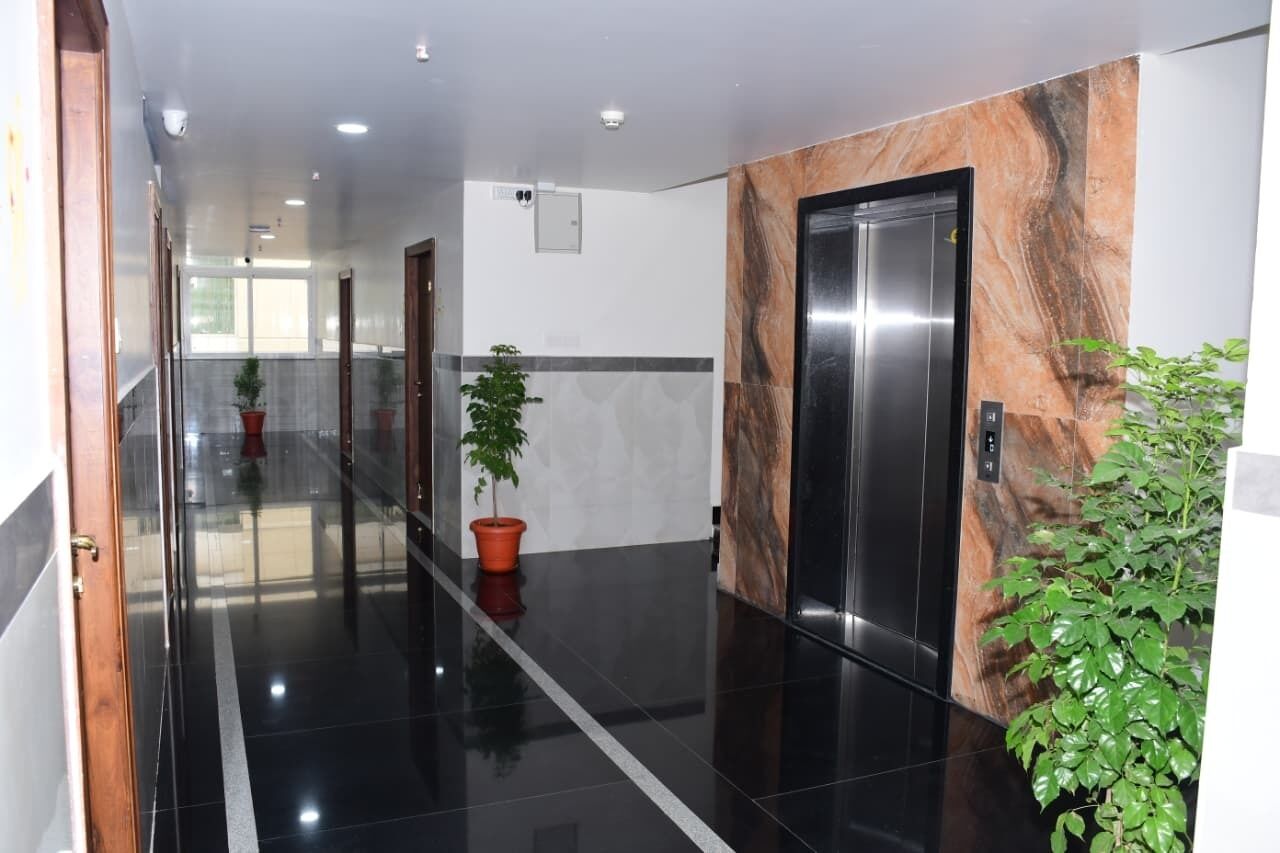 A modern hallway with a polished floor, a marble wall, and a potted plant.