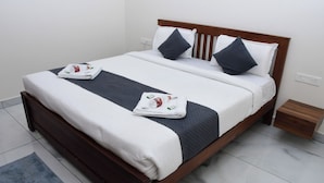 A neatly made bed with a dark-colored headboard, white bedding, and two dark pillows. - P A R GRAND LUXURY HOTEL  (ANANTHAPURAMU)