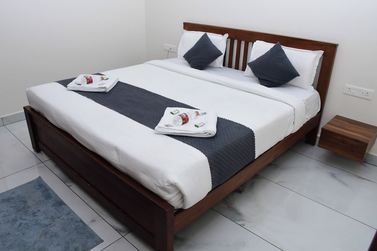Una cama bien hecha con un cabecero oscuro, ropa de cama blanca y dos almohadas oscuras.