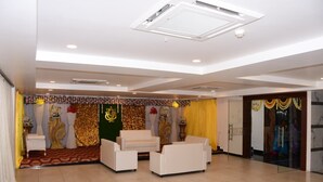 A spacious room with a seating area, a decorative backdrop, and a glass door leading to another room. - P A R GRAND LUXURY HOTEL  (Anantapur)