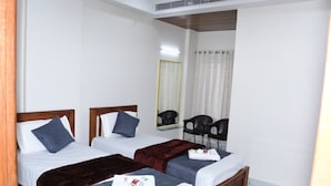 A hotel room with two single beds, a mirror, a chair, and a small table. - P A R GRAND LUXURY HOTEL  (ANANTHAPURAMU)