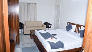A hotel room with a bed, a sofa, a chair, and a wooden wardrobe. - P A R GRAND LUXURY HOTEL  (ANANTHAPURAMU)
