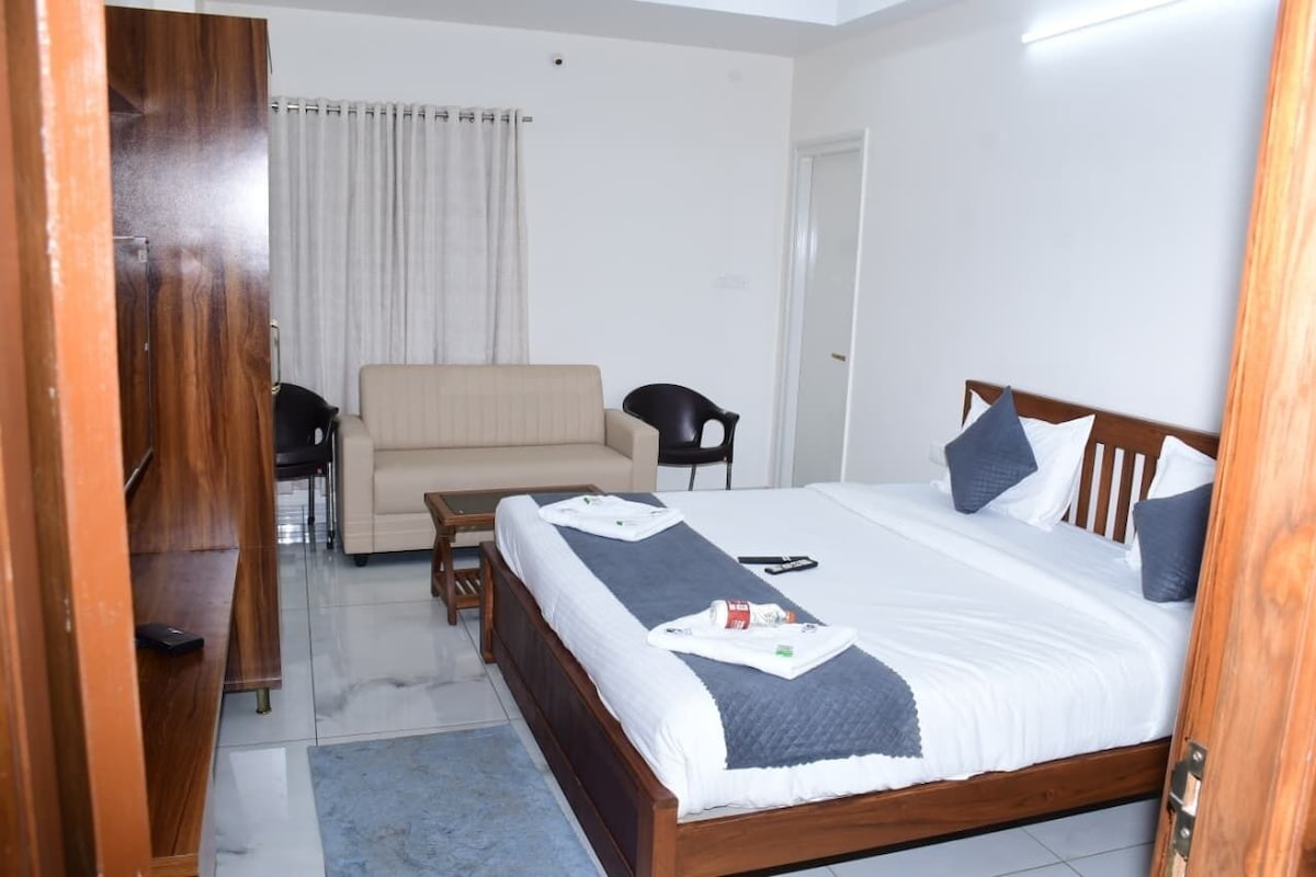 Una habitación de hotel con una cama, un sofá, una silla y un armario de madera.
