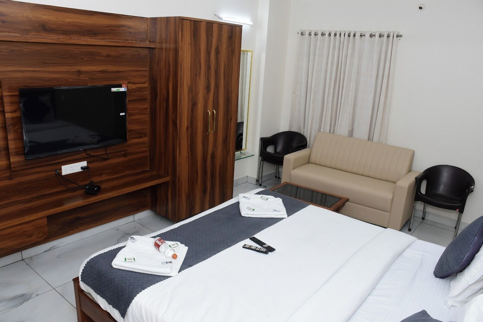 A hotel room with a bed, a TV, a sofa, and a small table.