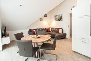 Ein zeitgemäßer Wohnraum mit Essbereich, einer Couch und einer Küche.