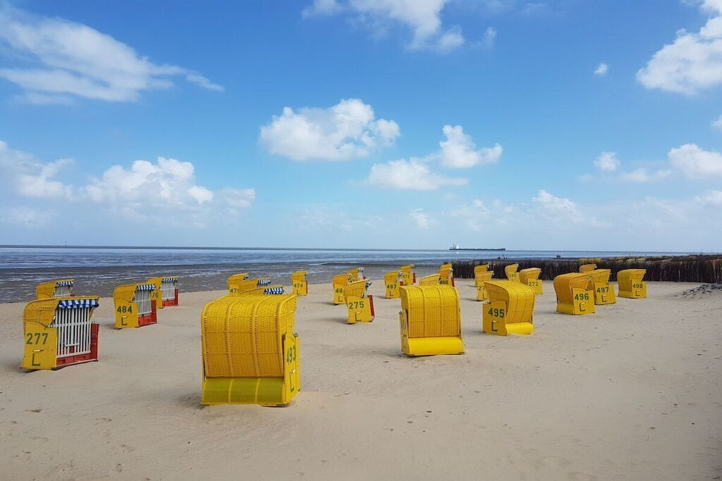 A beach with yellow beach huts numbered sequentially from 277 to 498.