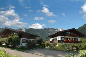 Two traditional chalet-style buildings with balconies, set against a mountainous backdrop. - Am Sonneneck - Apartment 1 (Ruhpolding)