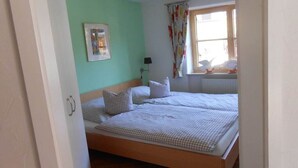 Habitació amb un llit, una làmpada, una finestra amb cortines i un quadre amb marc a la paret.