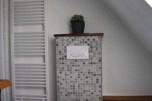 A corner of a room with a tiled wall, a small potted plant on top, and a white electrical outlet. - Holiday apartment with 1 bedroom (Butjadingen - Tossens)