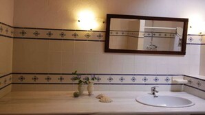A bathroom with a white sink, a mirror, and decorative tiles. - Holiday home with 3 bedrooms (Cabanas de Tavira)