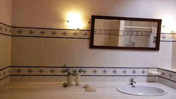 Casa de banho com lavatório branco, espelho e azulejos decorativos.