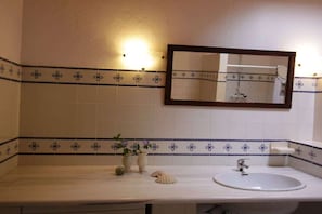 Ein Badezimmer mit einem weißen Waschbecken, einem Spiegel und dekorativen Fliesen.
