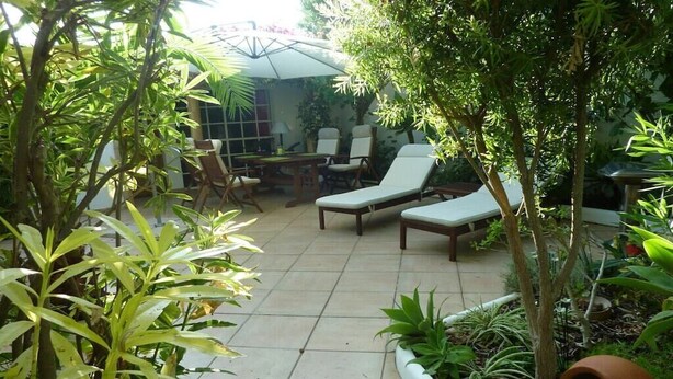 A patio area with a table and chairs, surrounded by plants and trees. - Holiday home with 3 bedrooms (Cabanas de Tavira)