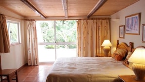 A bedroom with a bed, two bedside lamps, a wooden headboard, a window with curtains, and a door. - Holiday home with 3 bedrooms (Cabanas de Tavira)