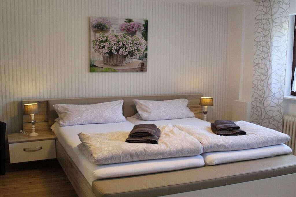 Een hotelkamer met een bed, twee bedlampen, een schilderij aan de muur en een raam met gordijnen.