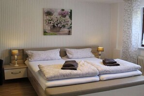 Een hotelkamer met een bed, twee bedlampen, een schilderij aan de muur en een raam met gordijnen.