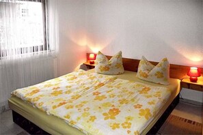 A bed with floral bedding, two bedside lamps, and a window with curtains. - Holiday apartment with 1 bedroom (Bad Schandau Stadtteil Prossen)