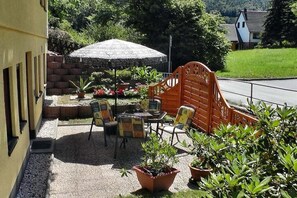 An outdoor seating area with tables and chairs, surrounded by potted plants and a decorative fence. - Holiday apartment with 1 bedroom (Bad Schandau Stadtteil Prossen)
