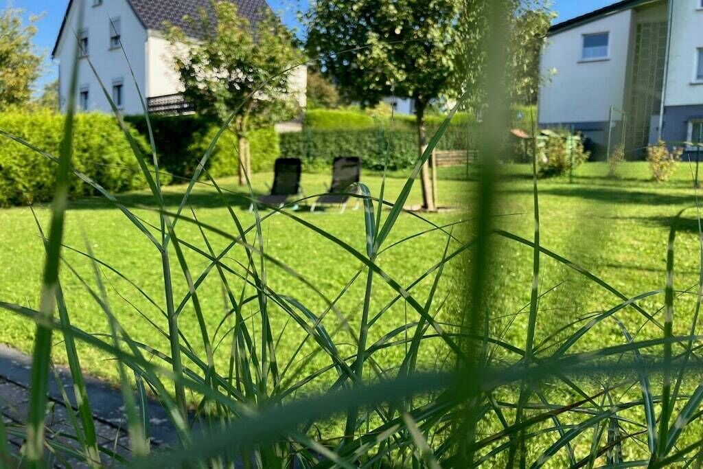 Ein Wohngebiet mit gepflegtem Rasen, zwei Liegestühlen und einem weißen Gebäude im Hintergrund.