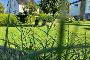 A residential area with a well-maintained lawn, two lounge chairs, and a white building in the background. - Country House Moments in Olsberg (Olsberg)