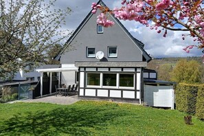 A modern two-story house with a large patio area, satellite dish, and a view of the surrounding landscape. - Country House Moments in Olsberg (Olsberg)