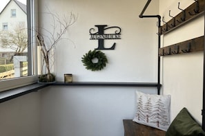 A room with a window, a wall-mounted wreath, a decorative letter 'E', and a coat rack with hooks. - Country House Moments in Olsberg (Olsberg)