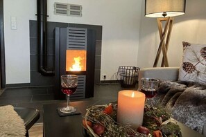 A cozy living room with a fireplace, a candle, and a glass of red wine on a table. - Country House Moments in Olsberg (Olsberg)