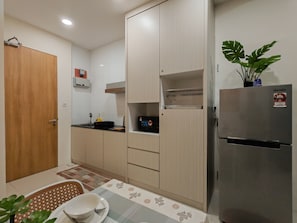 Una cocina compacta con refrigerador, microondas y pileta.