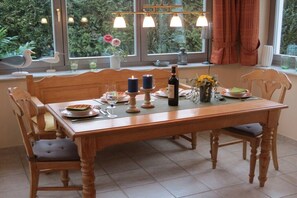 A dining table set with candles, a bottle, and a vase with flowers. - Holiday apartment Zaunkönig (Ostseebad Zinnowitz)
