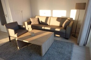 Ein modernes Wohnzimmer mit einer Couch, einem Sessel und einem Couchtisch.