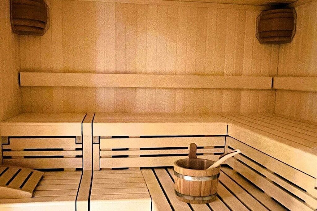 A sauna with wooden benches and a wooden bucket with a handle.