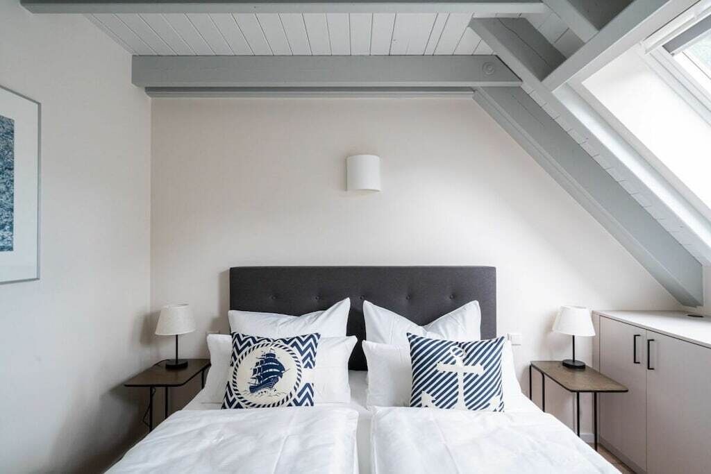 Une chambre à coucher avec un grand lit, deux tables de chevet avec des lampes, une tête de lit et une lucarne.