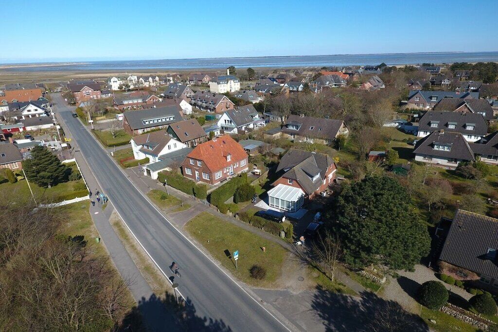 A residential area with houses, a road, and a body of water in the background.