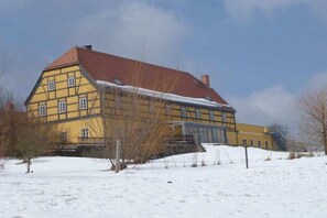 A large, yellow building with a red roof, surrounded by snow. - Holiday apartment with 1 bedroom (Gohrisch OT Papstdorf)