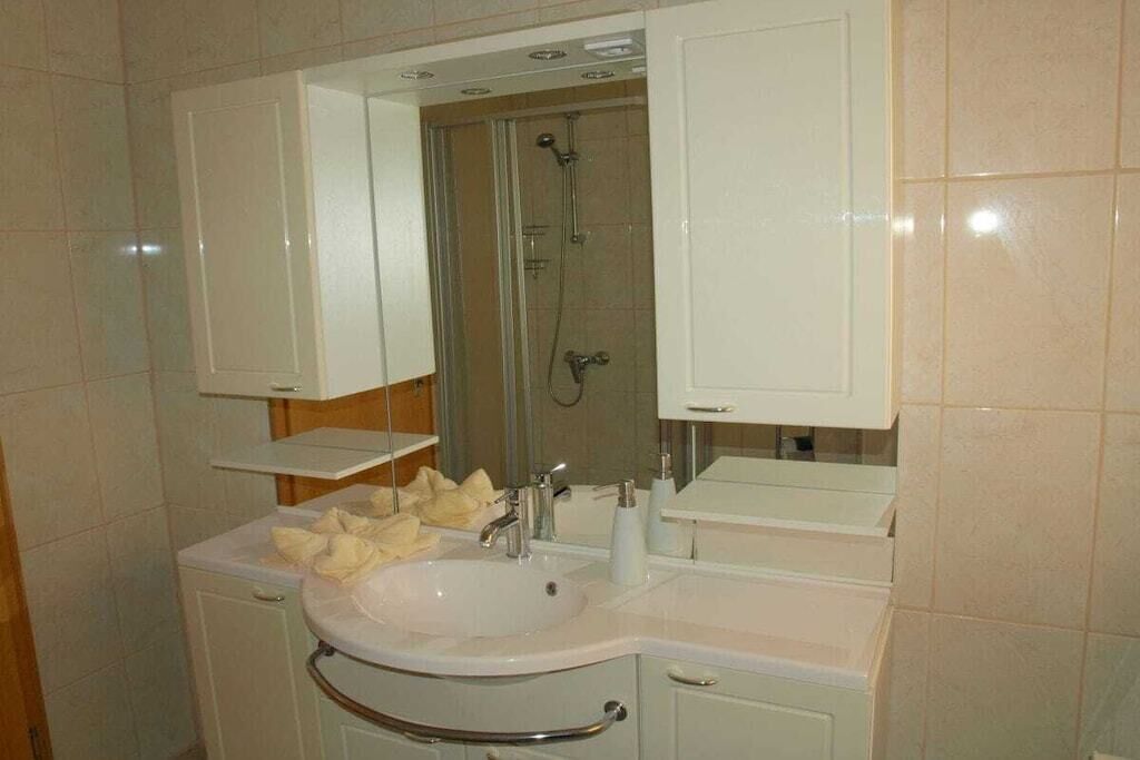 Une salle de bain avec un lavabo blanc, un miroir et une douche.
