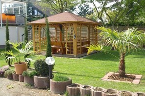 A wooden gazebo with a tiled roof, surrounded by potted plants and a well-maintained lawn. - Mengelberg in the Leipzig New Lake District (Markkleeberg)