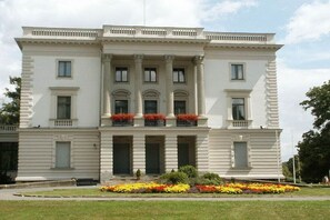 A large, stately building with a symmetrical facade, multiple windows, and a central entrance with columns. - Mengelberg in the Leipzig New Lake District (Markkleeberg)