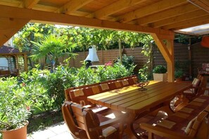 An outdoor wooden deck with a dining table and chairs, surrounded by lush greenery and a wooden fence. - Mengelberg in the Leipzig New Lake District (Markkleeberg)