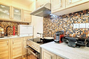 A kitchen with wooden cabinets, a stove, a microwave, and a tiled backsplash. - Luxury 4-bed Thalia apartment near Onassis Stegi - sleeps 10, 3.5 baths (Athina)