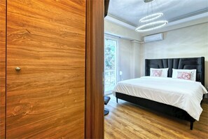 Ein Schlafzimmer mit einem Holzschrank, einem Bett mit dunklem Kopfteil und einer modernen Deckenleuchte.
