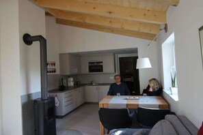 Eine kompakte Küche mit modernen Geräten, ein Essbereich mit Tisch und Stühlen sowie eine gemütliche Sitzecke mit einer Couch.