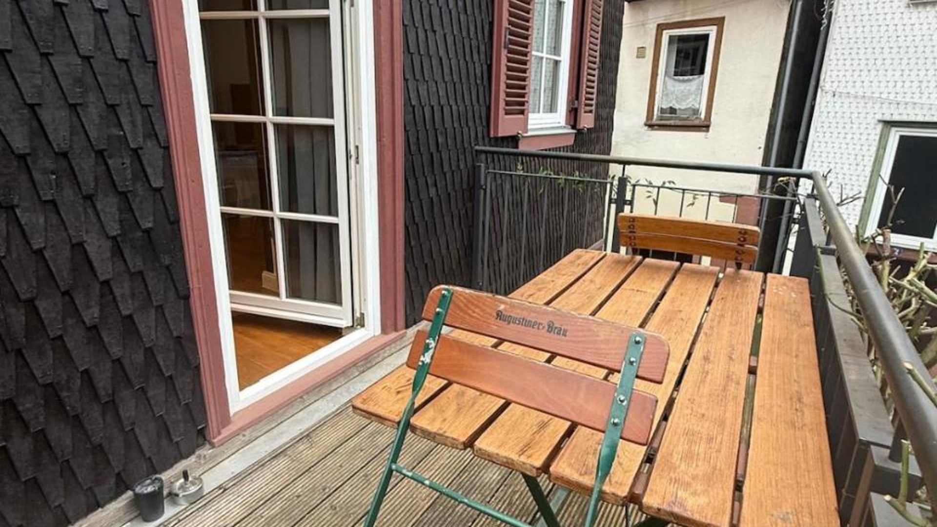 Ein Holztisch mit Stühlen, eine Schiebeglastür und ein kleines Fenster mit Rollläden.