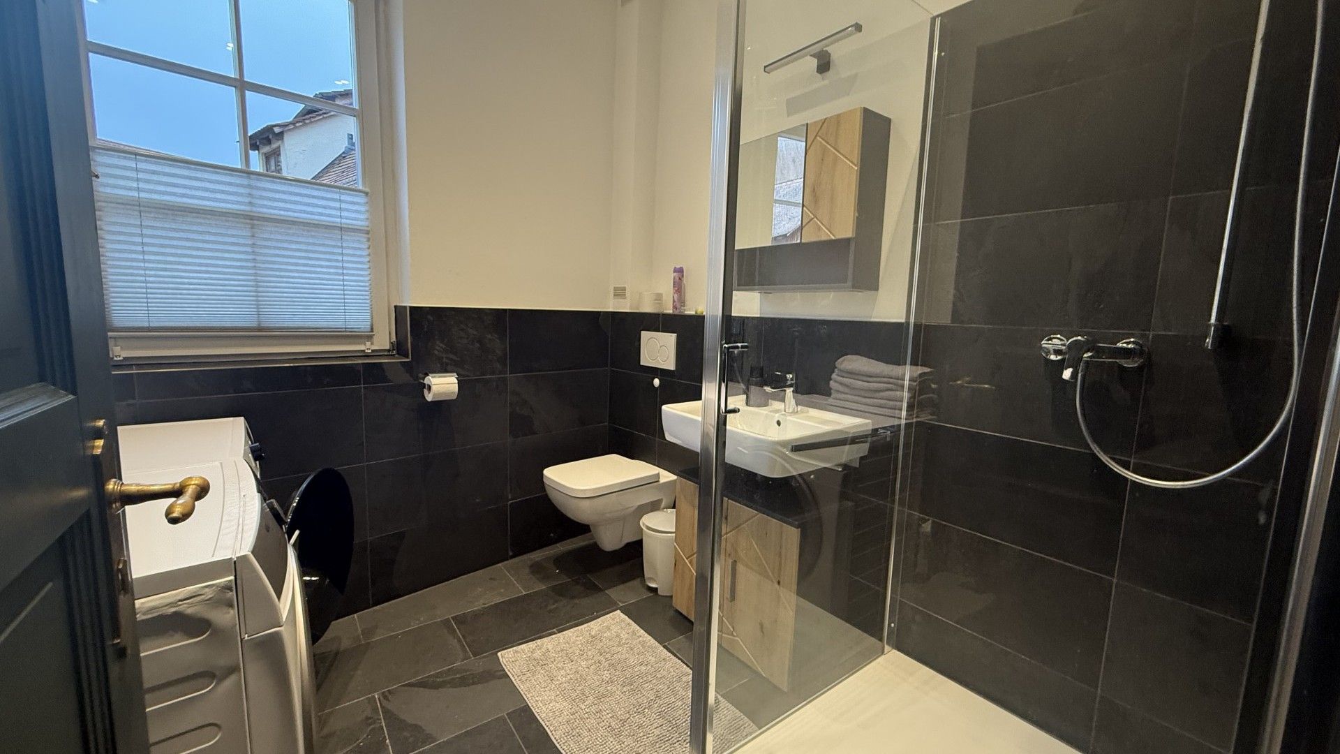 Ein modernes Badezimmer mit Duschkabine aus Glas, Toilette und Waschbecken.