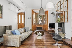 A living room with a sofa, a coffee table, a TV, and a fireplace. - 3 bed Spacious open plan house in Islington (London)