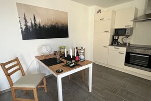 A small kitchen with a microwave, coffee maker, and a dining table with a chair. - Holiday apartment in Bad Bellingen with Wi-Fi (Bad Bellingen)