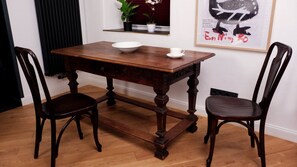 Una mesa de madera con dos sillas, un cuenco blanco y una taza encima.