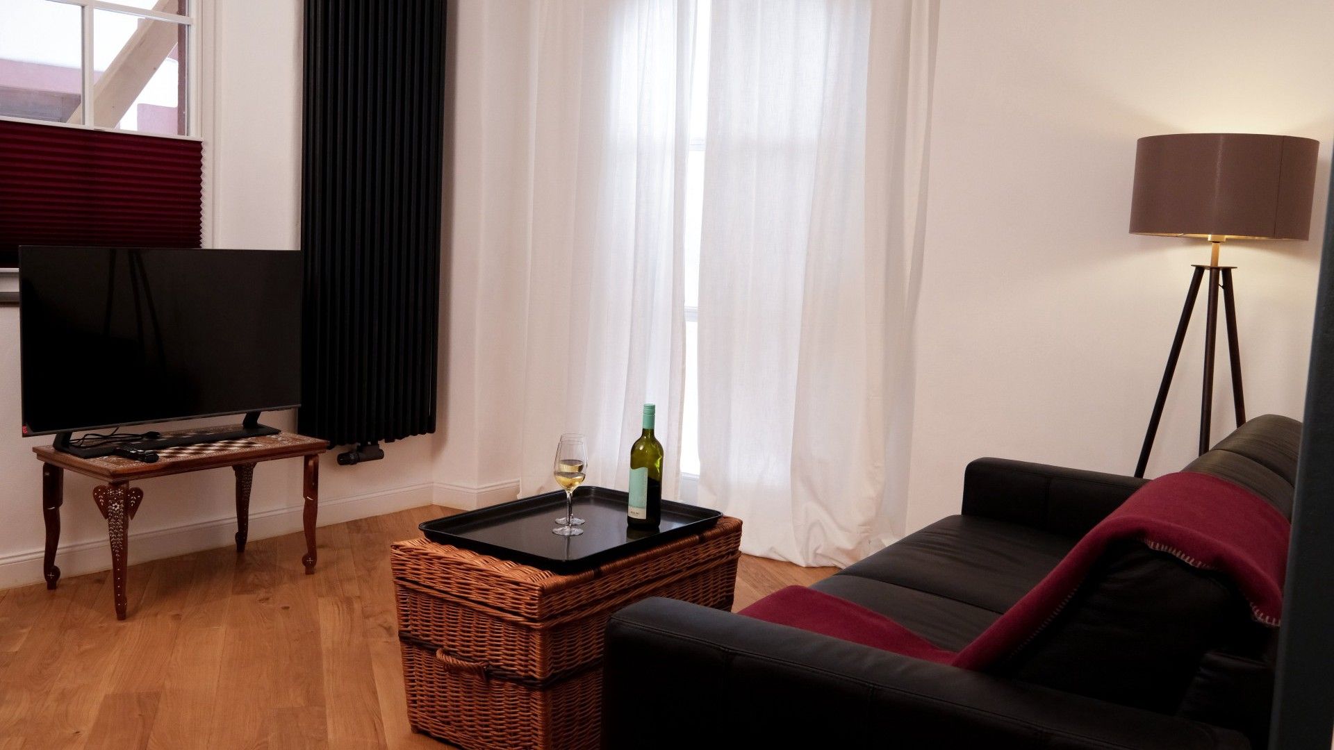 Un salon avec une télévision, un verre de vin, une lampe et un canapé.