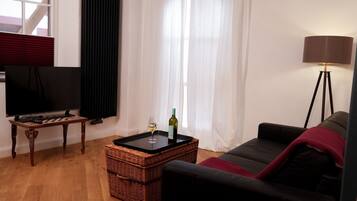 Un salon avec une télévision, un verre de vin, une lampe et un canapé.
