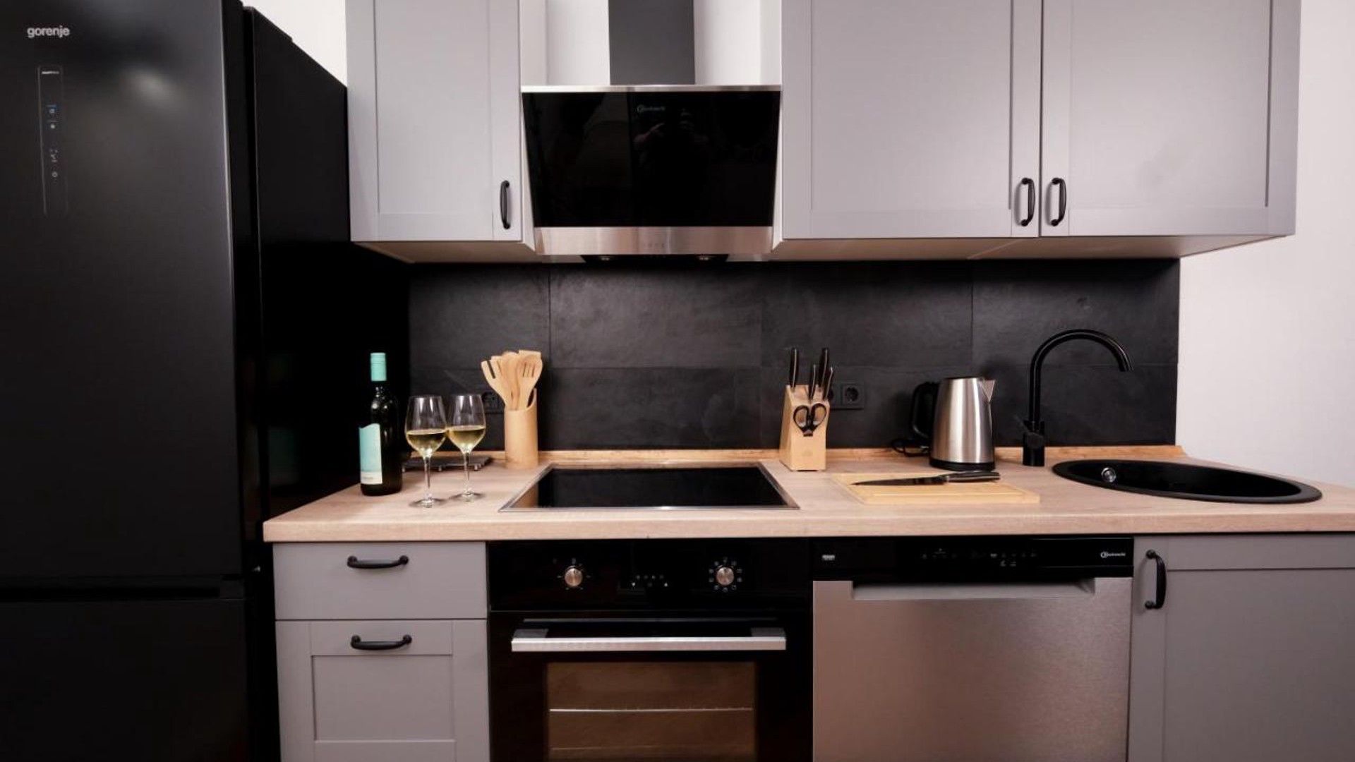 A modern kitchen with stainless steel appliances, a double sink, and wooden countertops.