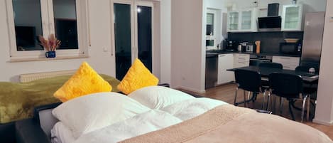 Un dormitorio moderno con una cama grande, dos almohadas, una mesita de noche y una ventana con vistas.